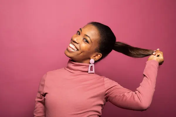 ピンクの背景に広く微笑んでいる若い美しいアフリカ系アメリカ人の若い女性のポートリア — ストック写真