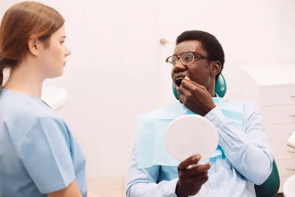 年轻黑人男性患者接受牙医治疗的肖像 女性专业口腔科医生 使用牙钻工具为年轻人提供服务 — 图库照片