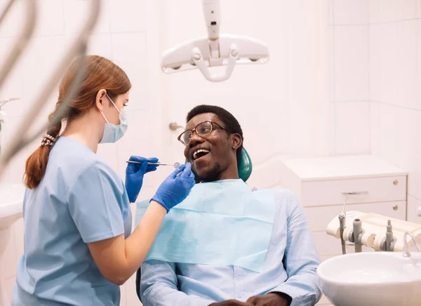 年轻黑人男性患者接受牙医治疗的肖像 女性专业口腔科医生 使用牙钻工具为年轻人提供服务 — 图库照片