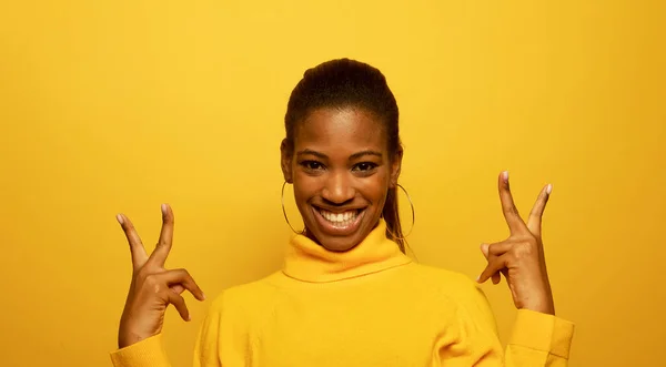 若い笑顔の黒人女性 20代は勝利の印で覆うことを示す黄色いセーターを着ます — ストック写真