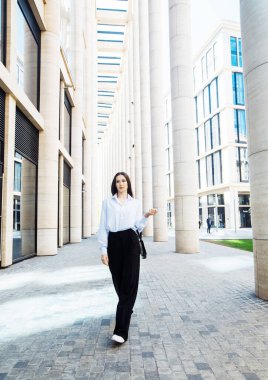 Siyah pantolonlu, beyaz pamuklu bluzlu, dışarıda poz veren şık bir kadın manken. Kadın modası. Şehir yaşam tarzı.