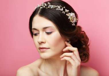 Beautiful young bride with fashion wedding hairstyle. Portrait of young woman over pink background.