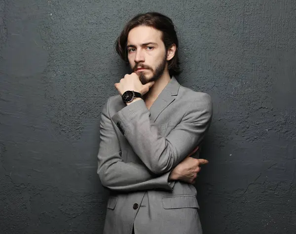 Gri duvar arkasında poz veren genç yakışıklı adam.