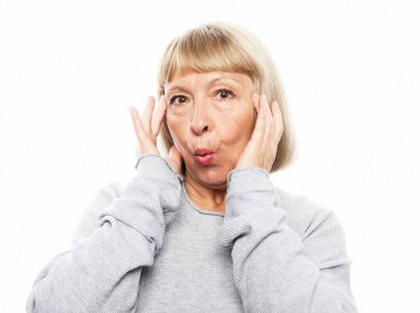 Beyaz arka planda kameraya bakan şok olmuş olgun bir kadının yakın plan portresi.