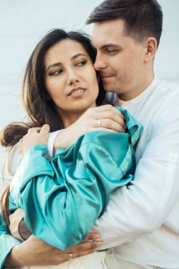 Farklı milletten aşık genç ve mutlu bir çift nehir kenarında sarılıp öpüşüyor. Asyalı kadın ve Avrupalı erkek. Aşk ve aile kavramı.