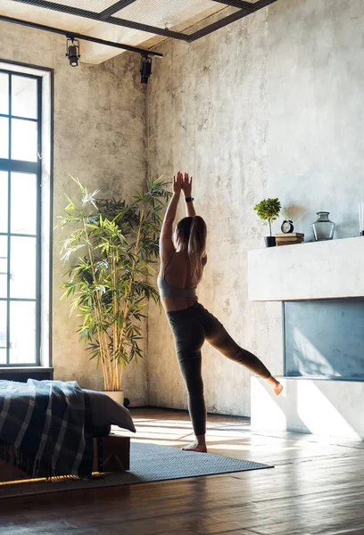 A young woman is engaged in aerobics with her health doing stretching and cardio exercises. Workout fitness gym at home in the living room, comfortable sportswear.