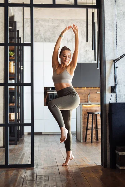 A young woman is engaged in aerobics with her health doing stretching and cardio exercises. Workout fitness gym at home in the living room, comfortable sportswear.