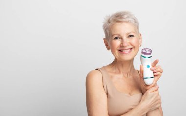 60 'ların güzel kadını elinde bir masaj aleti tutuyor. Spa tekniği cilt bakımı reklamları.