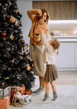 Aile, kış tatili ve insanlar konsepti. Mutlu anne ve küçük kız evde Noel ağacı süslüyorlar..