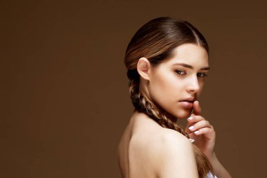 Kahverengi arka planda sağlıklı bir cildi olan genç ve çekici bir kadının yakın plan portresi. Güzellik ve insan konsepti.