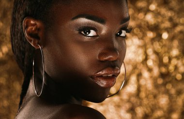 Beauty portrait of a sensual African woman over gold background. Close up.