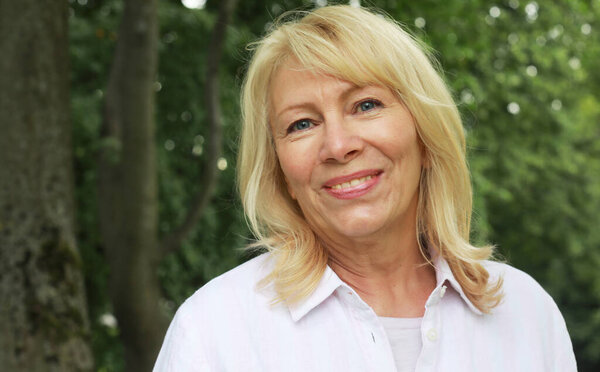 Красивая блондинка шестидесяти лет в летнем парке, портрет крупным планом. Леди улыбается и чувствует себя счастливой. Золотой век.