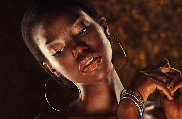 Beauty portrait of a sensual African woman over gold background. Close up.