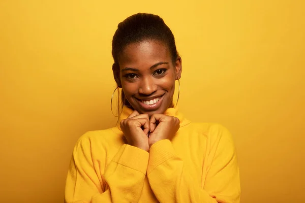 Lifestyle, emotion and people concept: Close up portrait of beautiful young african woman laughing over yellow background