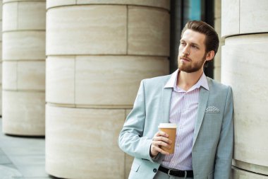 Yeni güne taze kahveyle başlıyoruz. Bıyıklı, şık takım elbiseli, mutlu ve yakışıklı bir iş adamı elinde kahve, sabah ofisine gidiyor..