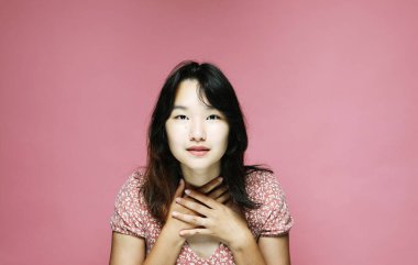 Genç Asyalı kadın şaşkın, pembe arka planda heyecan verici duygular yaşıyor, yakın plan