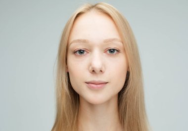 Gri arka planda izole edilmiş neşeli genç bir kadının portresi.