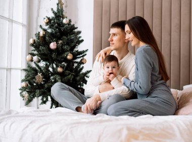 Mutlu, genç bir aile - anne ve baba küçük kızıyla birlikte Noel ağacının yanında, eğlen, mutlu aile hayatının tadını çıkar.