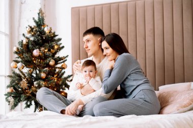 Mutlu, genç bir aile - anne ve baba küçük kızıyla birlikte Noel ağacının yanında, eğlen, mutlu aile hayatının tadını çıkar.