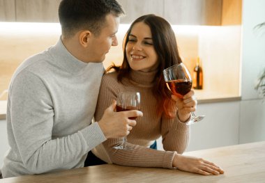 Aşık genç çift mutfakta kırmızı şarap içiyor. Rahat bir ev. Aşk ve romantik konsept.