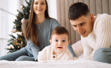 Küçük bir kızı olan genç bir aile, yatağa uzan ve eğlen. Çocukluk, aşk ve aile kavramı.