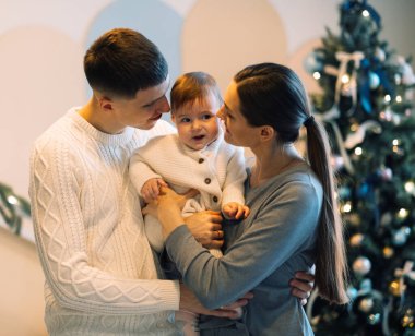 Mutlu bir baba, karısının yanında durur, kucağında küçük bir kız bebek, Noel konsepti.