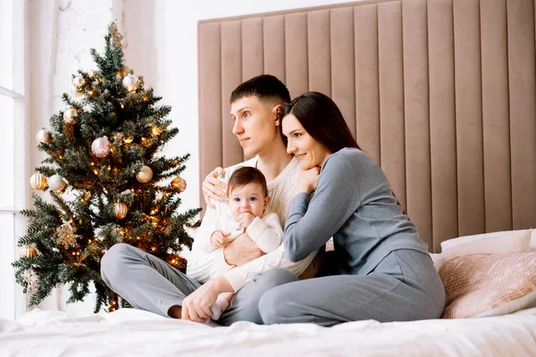 快乐的年轻家庭 爸爸妈妈和小女儿一起坐在圣诞树旁 玩得开心 享受快乐的家庭生活 — 图库照片