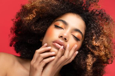 Kızıl arka planda afro saçlı, zarif bir Afrikalı Amerikalı kadın. Cazibe makyajı.