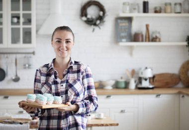 Marşmelov tutan genç fırıncı kadın. Mutlu, gülümseyen ve neşeli.