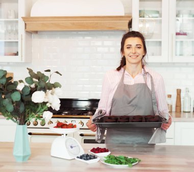 Elinde kek tutan genç fırıncı kadın. Mutlu, gülümseyen ve neşeli.