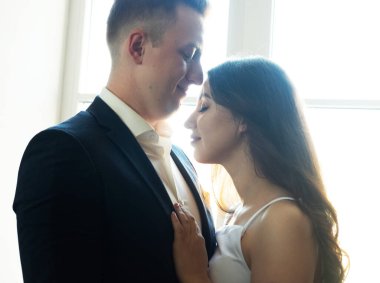 Zarif gelinlik içinde genç ve mutlu bir çift. Evlerinde birbirlerine nazikçe sarılıyorlar..