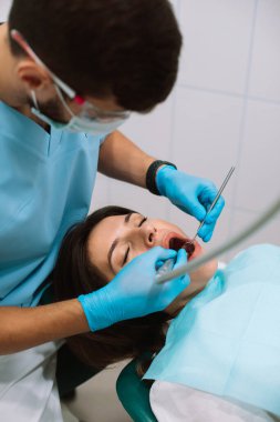 Genç erkek dişçi modern klinikte tedavi görüyor.