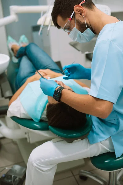 young male dentist making treatment in modern clinic