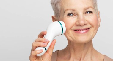 Güzel bir yüz portresi. Kısa saçlı, tatlı ve son sınıf öğrencisi bir kadın. Yüz masajını mükemmel bir cilt için kullanıyor.