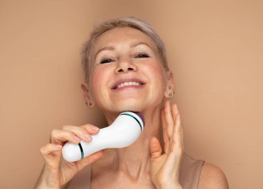 Güzel bir yüz portresi. Kısa saçlı, tatlı ve son sınıf öğrencisi bir kadın. Yüz masajını mükemmel bir cilt için kullanıyor.