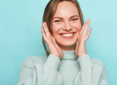 Neşeli genç bir kadının portresi mavi arka planda neşeli ve güler yüzlü.