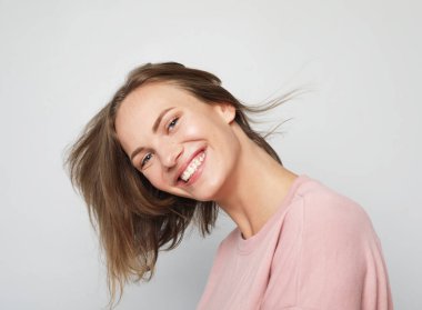 Gri arka planda gülümseyen güzel sarışın kadın. Portreyi kapat.