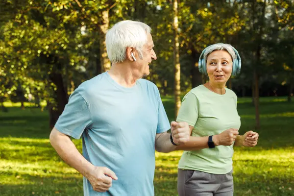 Smiling senior couple jogging in the park. Lifestyle, people and sport concept.