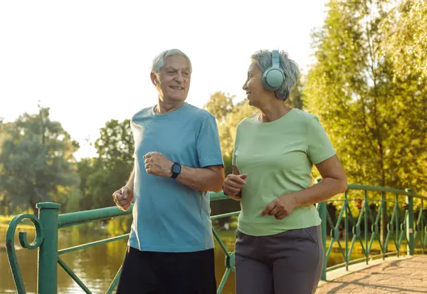 Smiling senior couple jogging in the park. Lifestyle, people and sport concept.