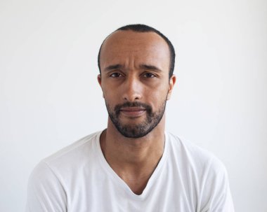 Genç afro adamın fotoğrafı gri arka planda beyaz tişört giyiyor.