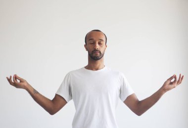Genç yakışıklı afro adam zihnine konsantre oluyor, meditasyon yapıyor, yoga yapıyor, nefes egzersizi yapıyor stresi azaltıyor..