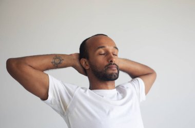 Genç yakışıklı afro adam zihnine konsantre oluyor, meditasyon yapıyor, yoga yapıyor, nefes egzersizi yapıyor stresi azaltıyor..