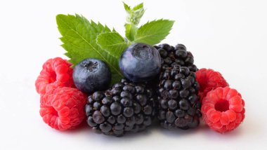 Yaprakla böğürtlen karıştır. Beyaz arka planda izole edilmiş çeşitli taze meyveler. Ahududu, yabanmersini, kızılcık, böğürtlen ve nane yaprakları. Kapat..