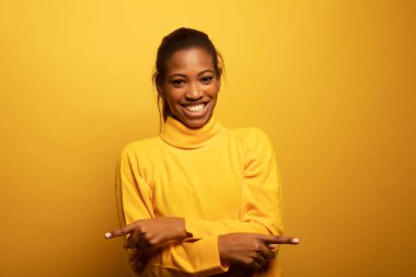 Sarı arka plan, yaşam tarzı ve insan kavramına gülen güzel Afrikalı genç bir kadının yakın portresi..