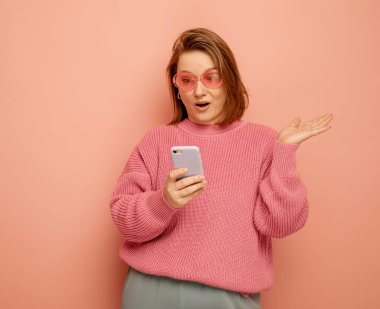 tehnoloji ve modern yaşlılar konsepti: Pembe arka planda cep telefonuyla konuşan şaşırmış bir kadının portresi