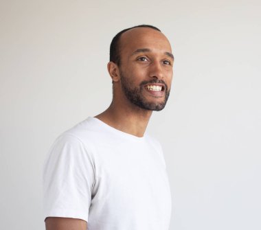 Açık gri arka planda traşsız genç bir adam. Karışık ırk yakışıklı erkek model. Portreyi kapat.