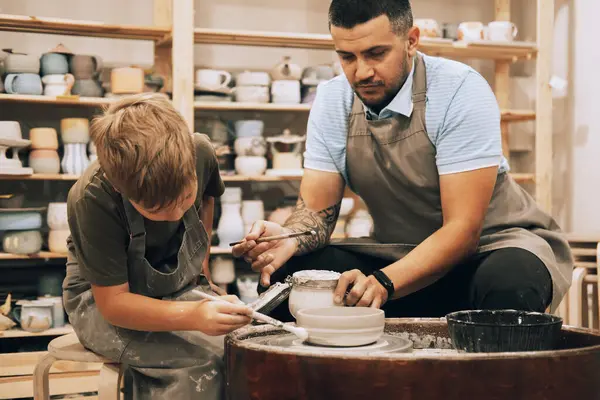陶器のクラスで陶器の鍋を作る若者と小さな少年を自信を持って ライフスタイルと人々のコンセプト — ストック写真