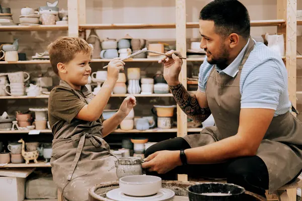 A young father and his seven-year-old son are engaged in creativity in a pottery workshop. Happy moments of joint activities with your child. Lifestyle concept.