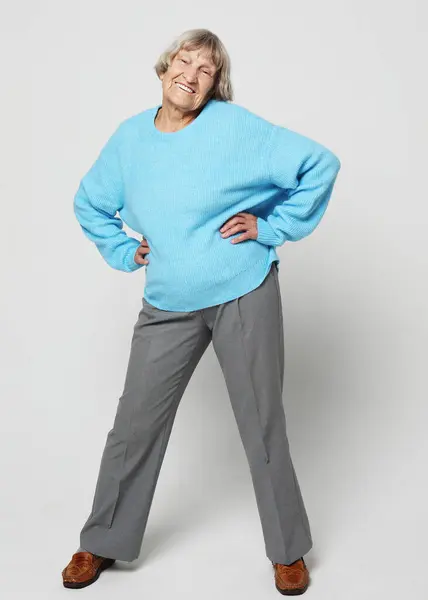 明るい灰色の背景にポーズブルーセーターの短い髪の古い女性 — ストック写真