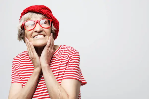 メガネと赤い帽子をかぶった古い女性の肖像画を手で閉じる — ストック写真